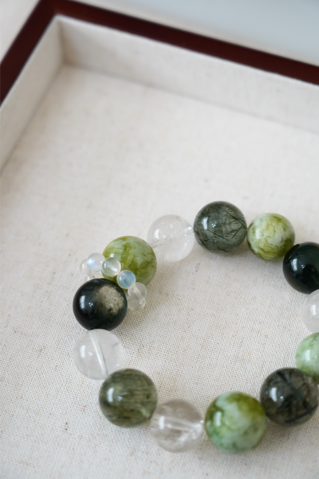 Beaded bracelet with green, black, and clear beads on a light background