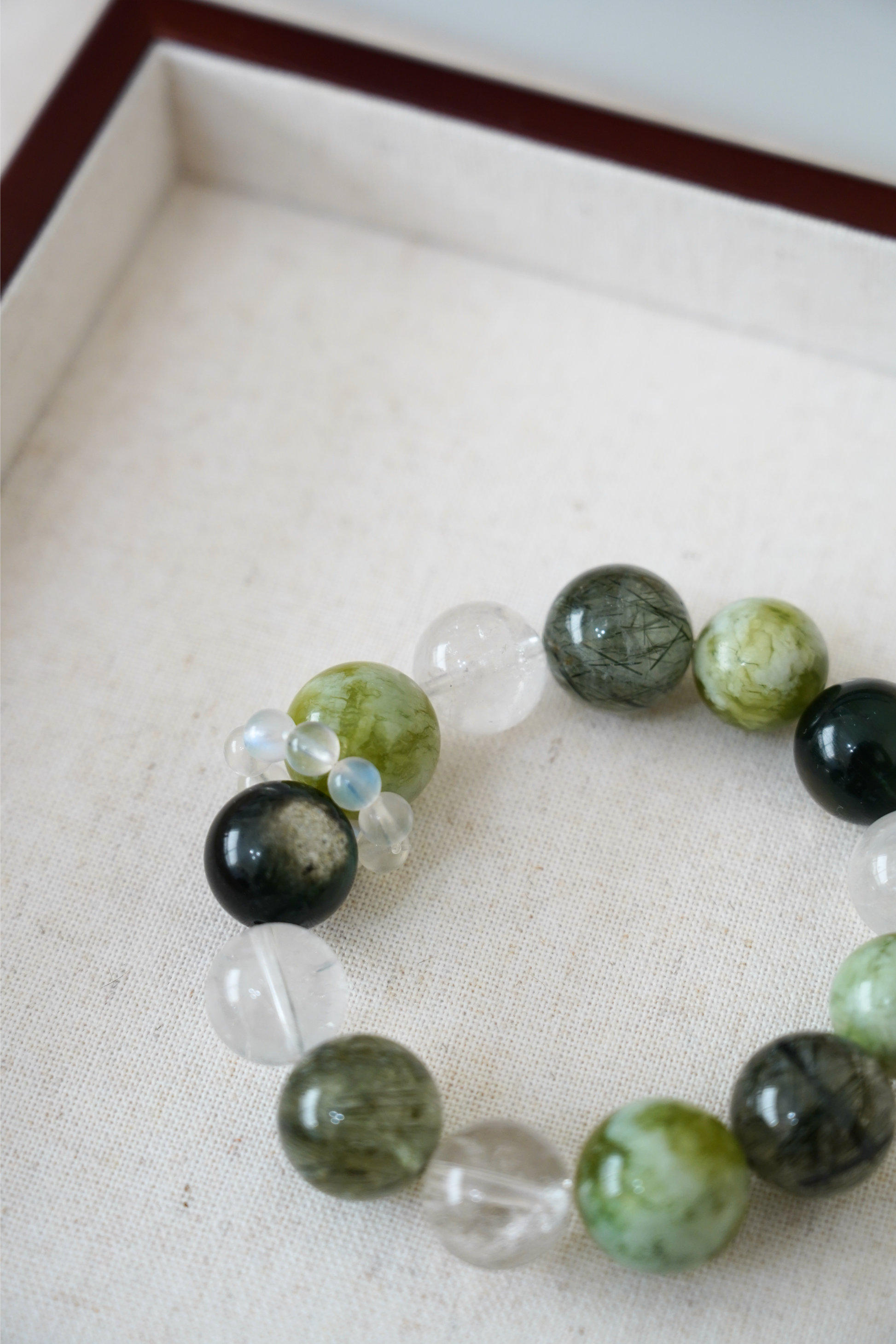 Beaded bracelet with green, black, and clear beads on a light background