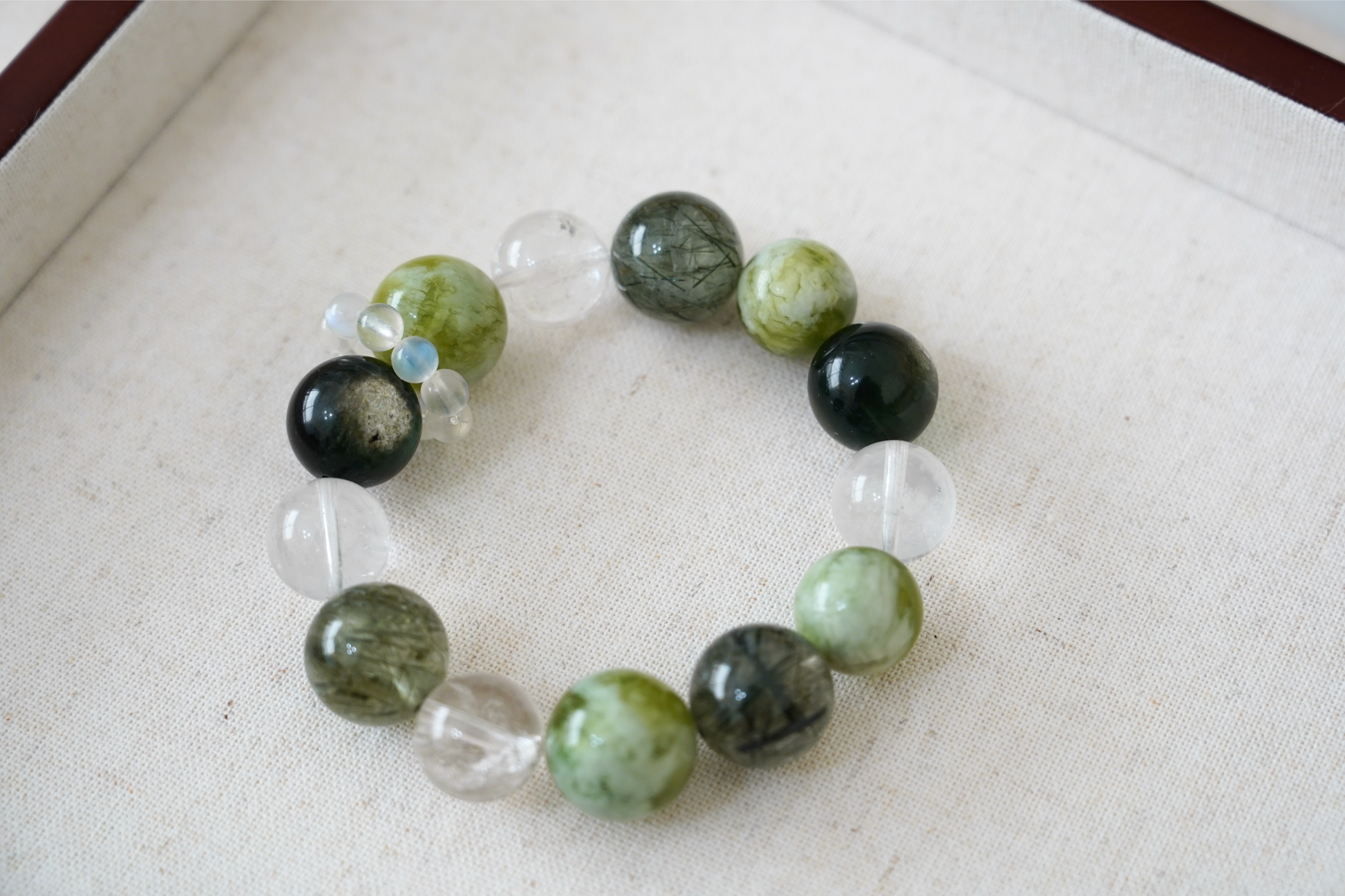 Bracelet with green and black beads on a white fabric background