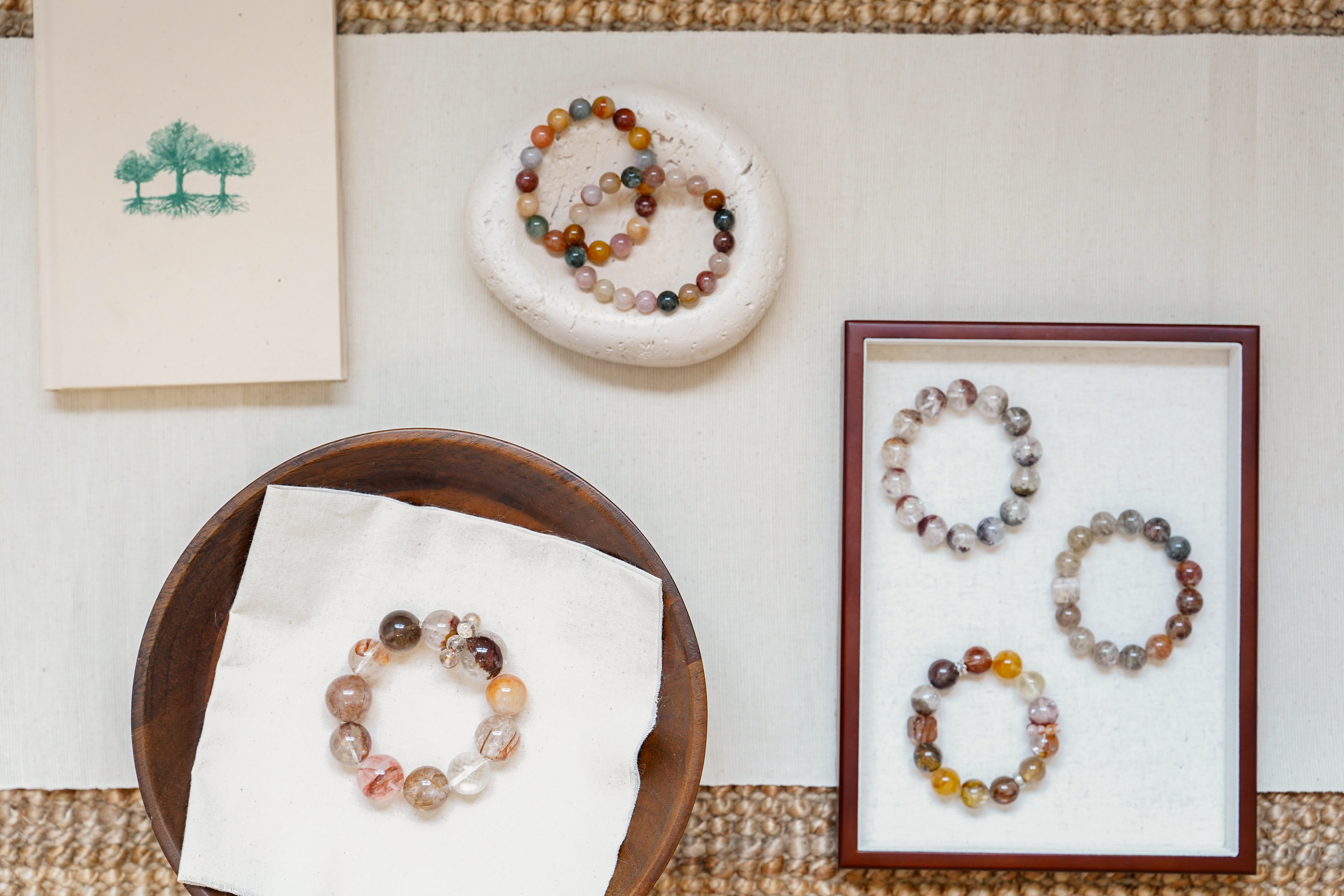 Beaded bracelets on a wooden plate and in a frame against a textured surface.