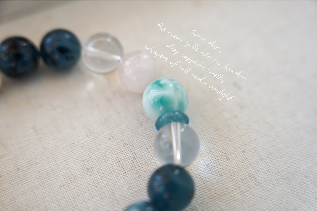 Close-up of a beaded crystal bracelet with blue, green, and clear beads on a textured surface.