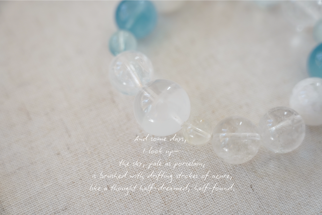 Beaded bracelet with clear and blue beads on a textured surface, accompanied by a poetic quote.