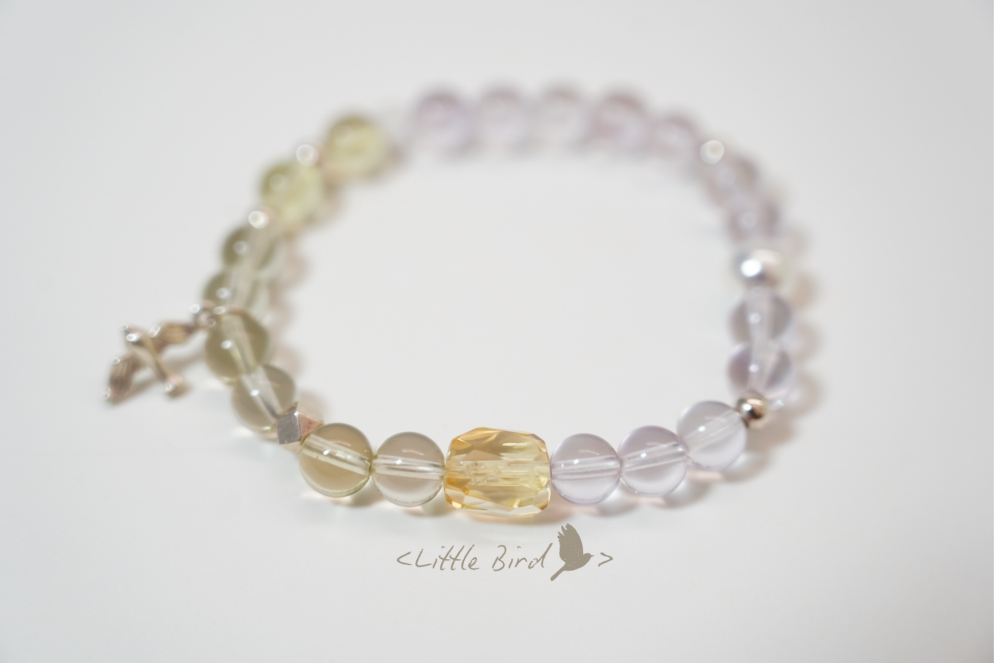 Beaded crystal bracelet with clear, yellow, and light purple beads on a white background