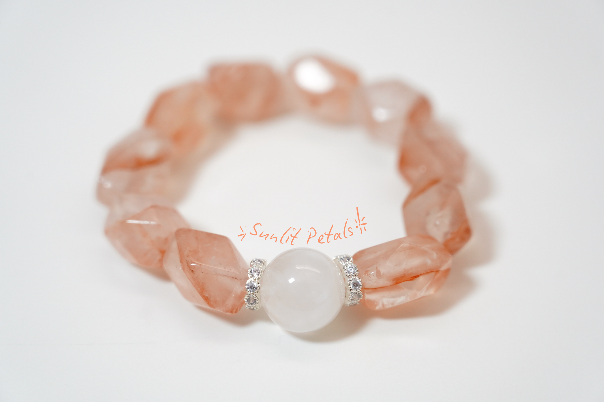 Pink stone bracelet with a central white bead on a light background