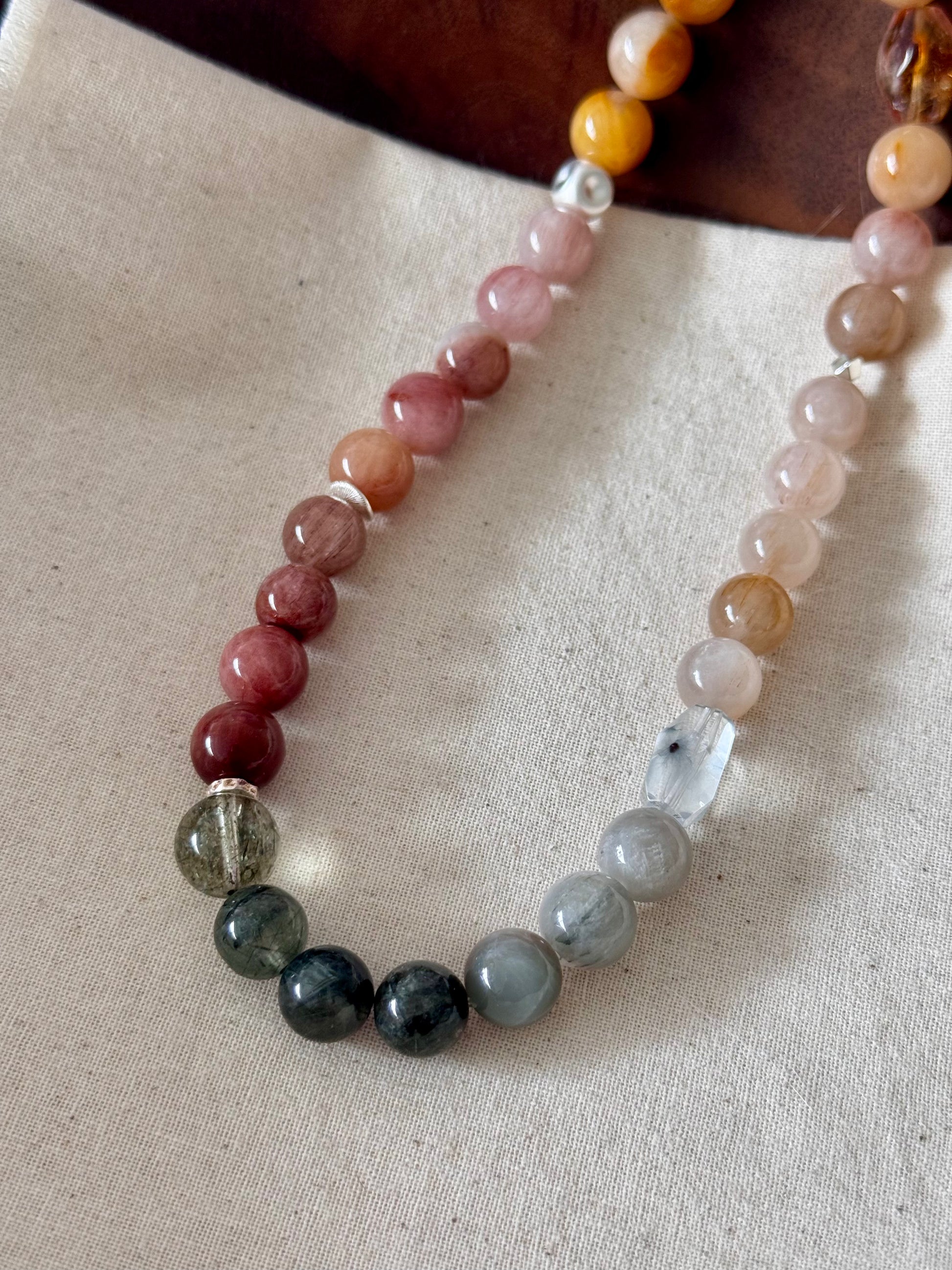 rutile quartz bracelet with multicolored beads on a beige fabric background