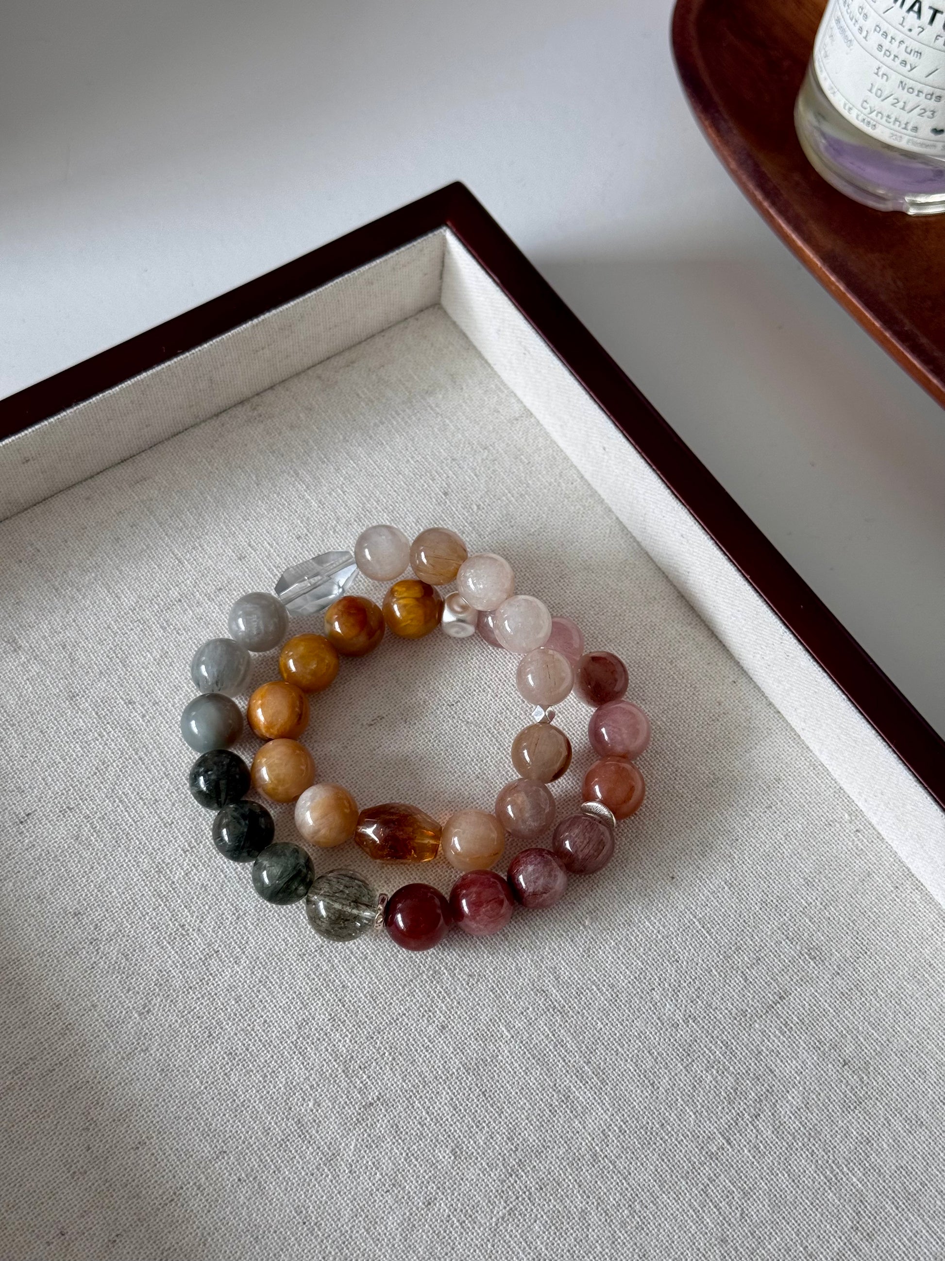 Stack of multicolored beaded rutile quartz bracelets on a textured surface