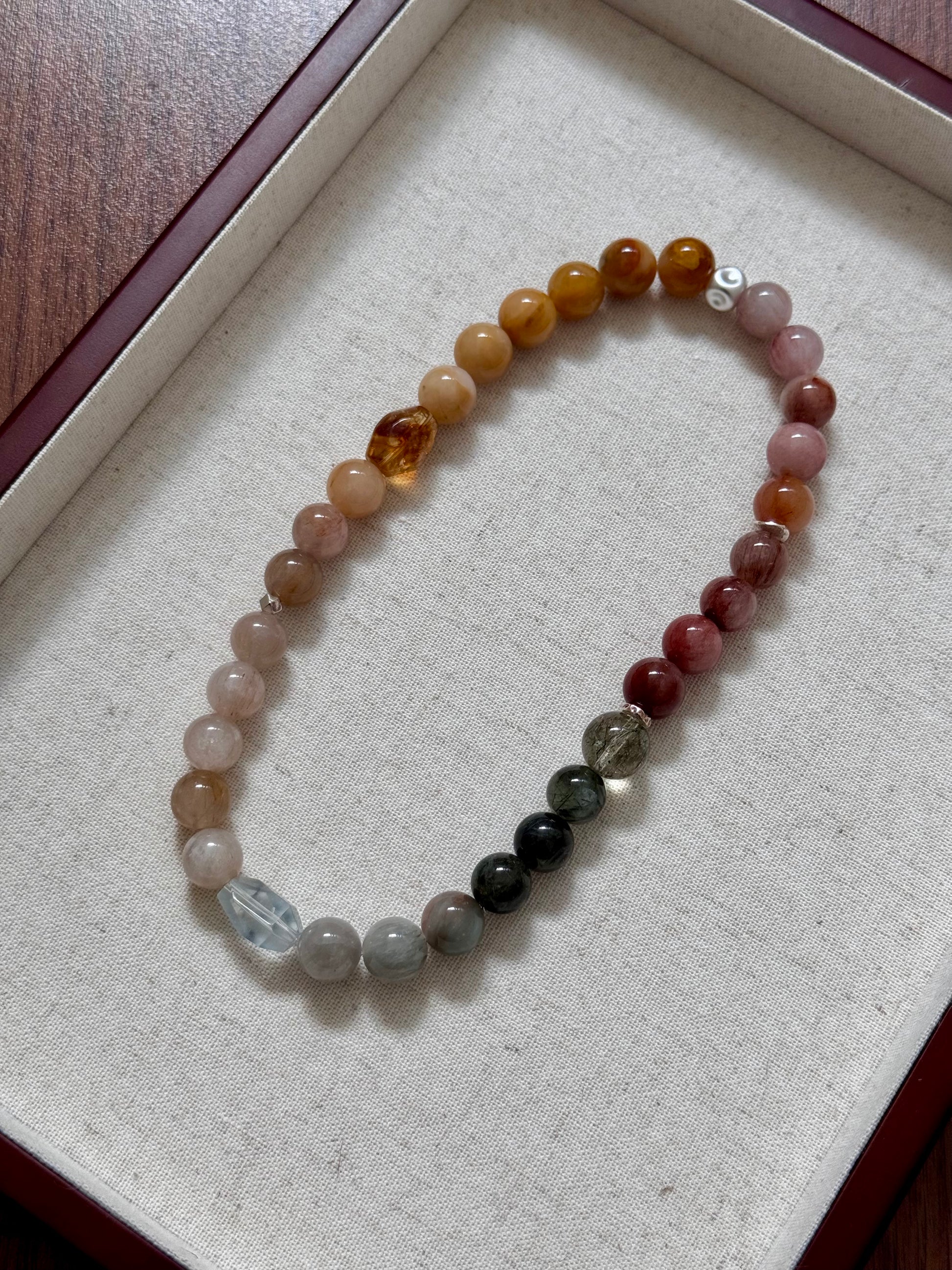 Multicolored beaded rutile quartz bracelet on a textured surface