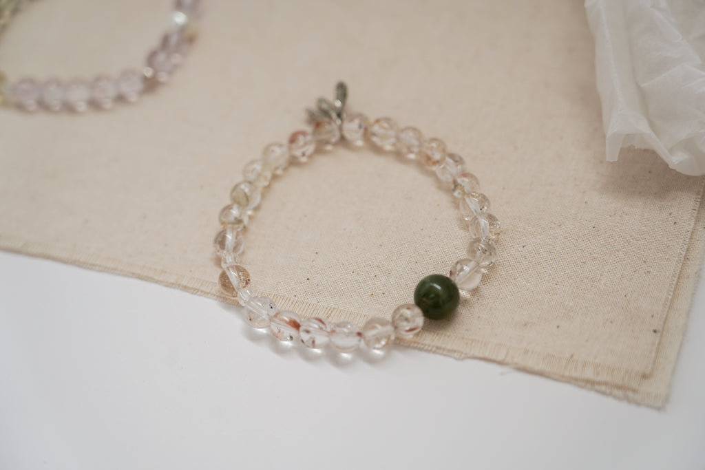 Crystal bracelet with a green bead on a beige fabric background