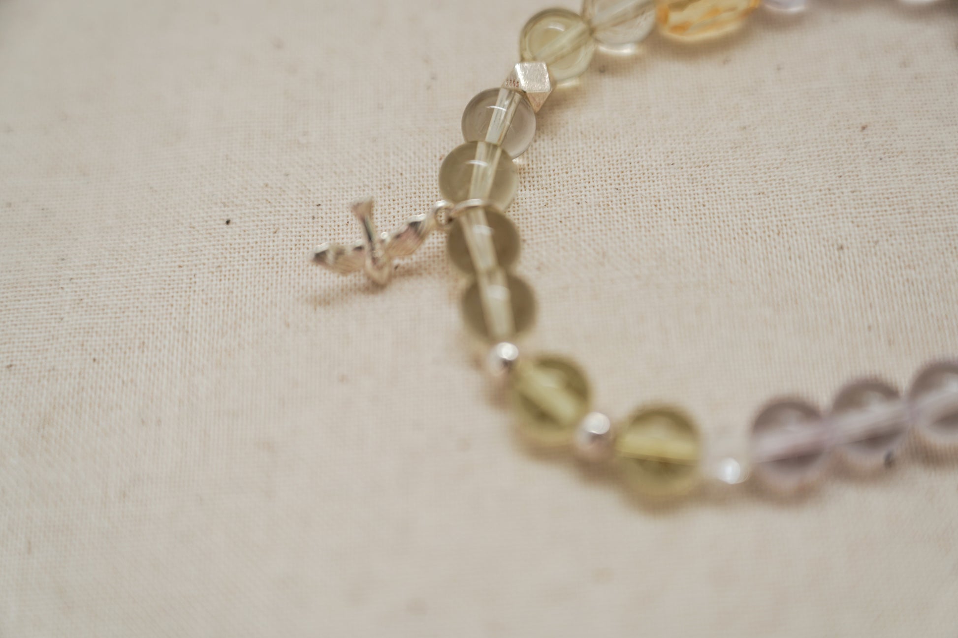 Close-up of a beaded crystal bracelet on a textured beige surface