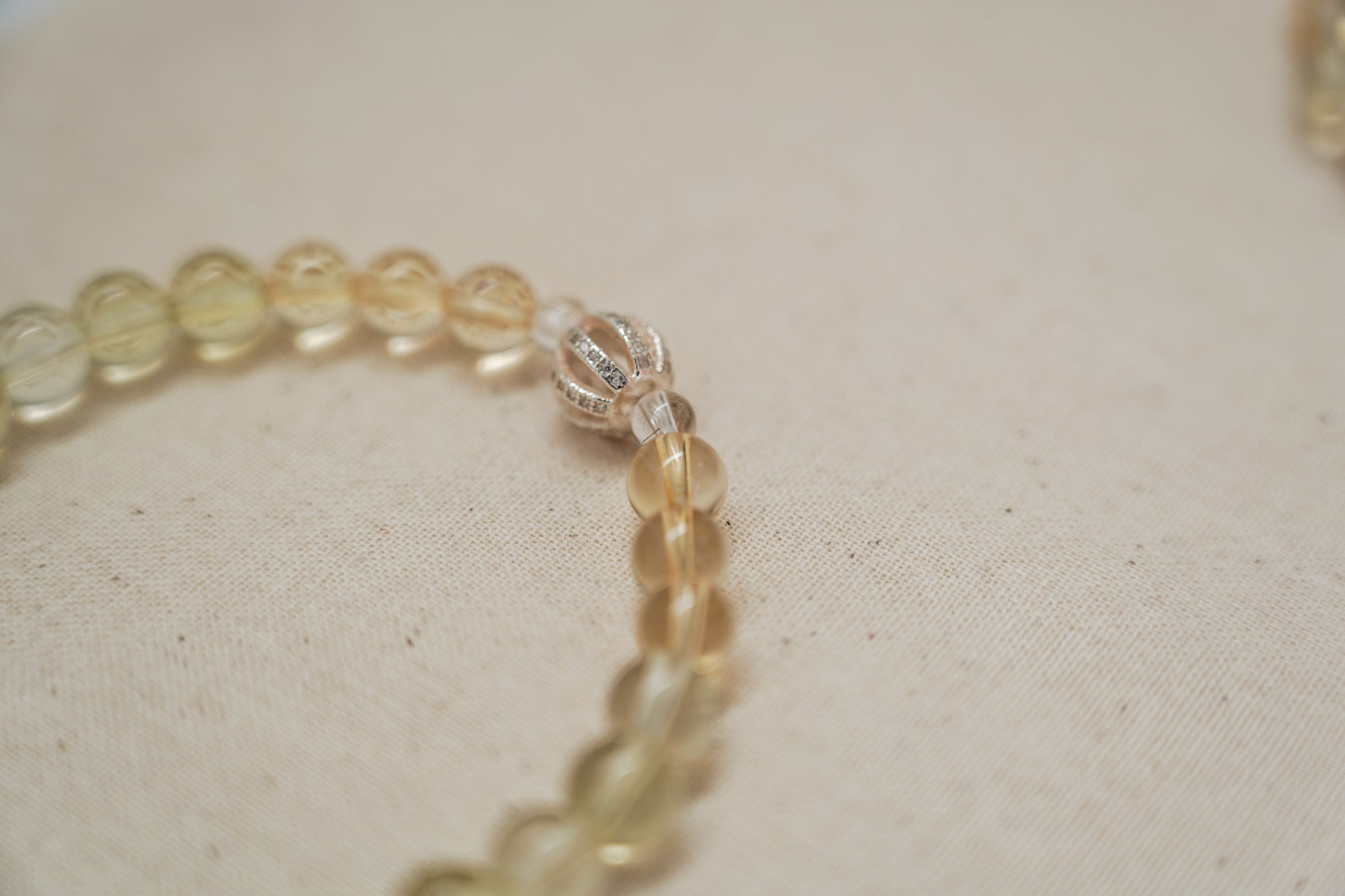 Close-up of a crystal bracelet with clear beads on a beige fabric background