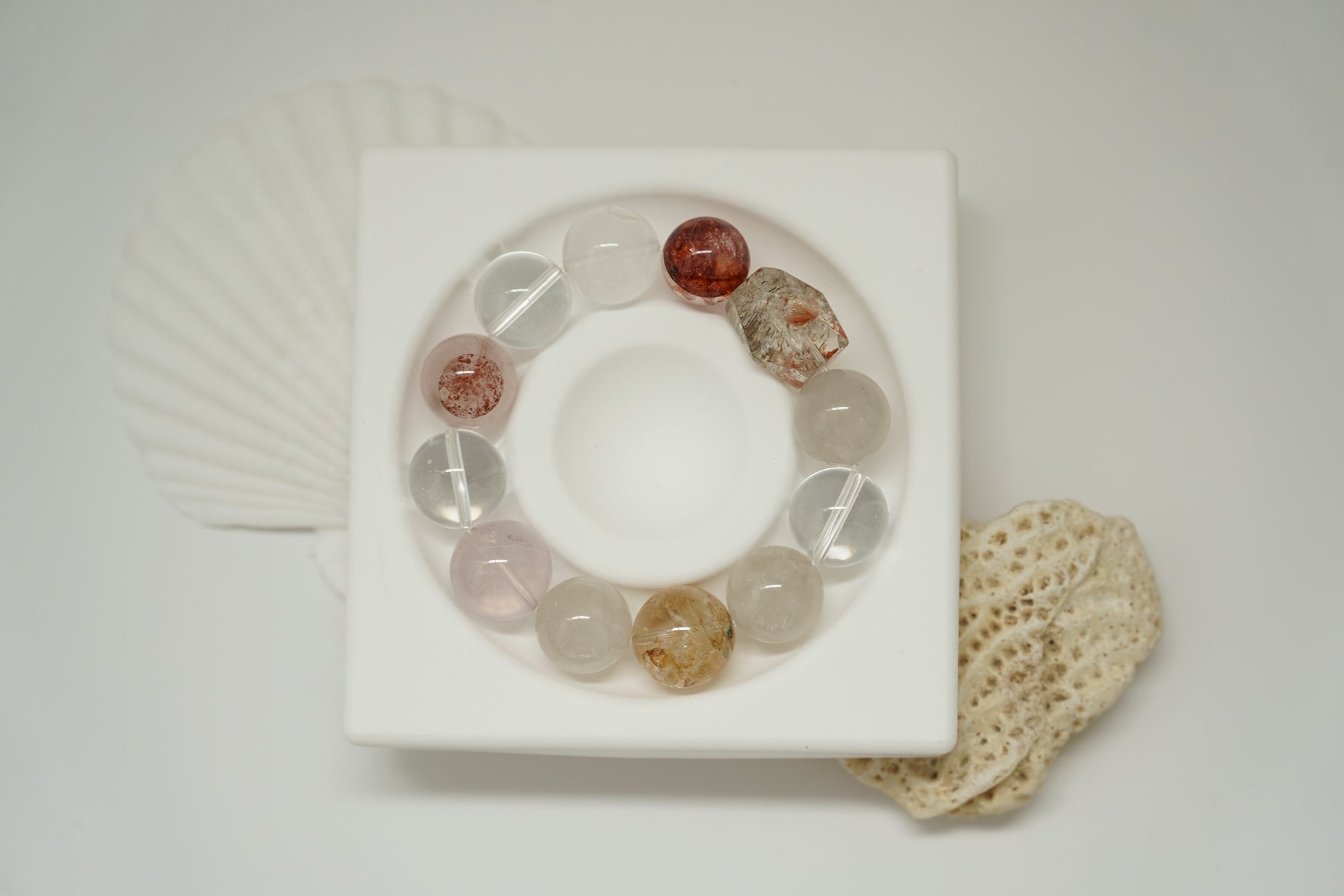 Crystal bracelet on a white square platform with a textured beige mat in the background