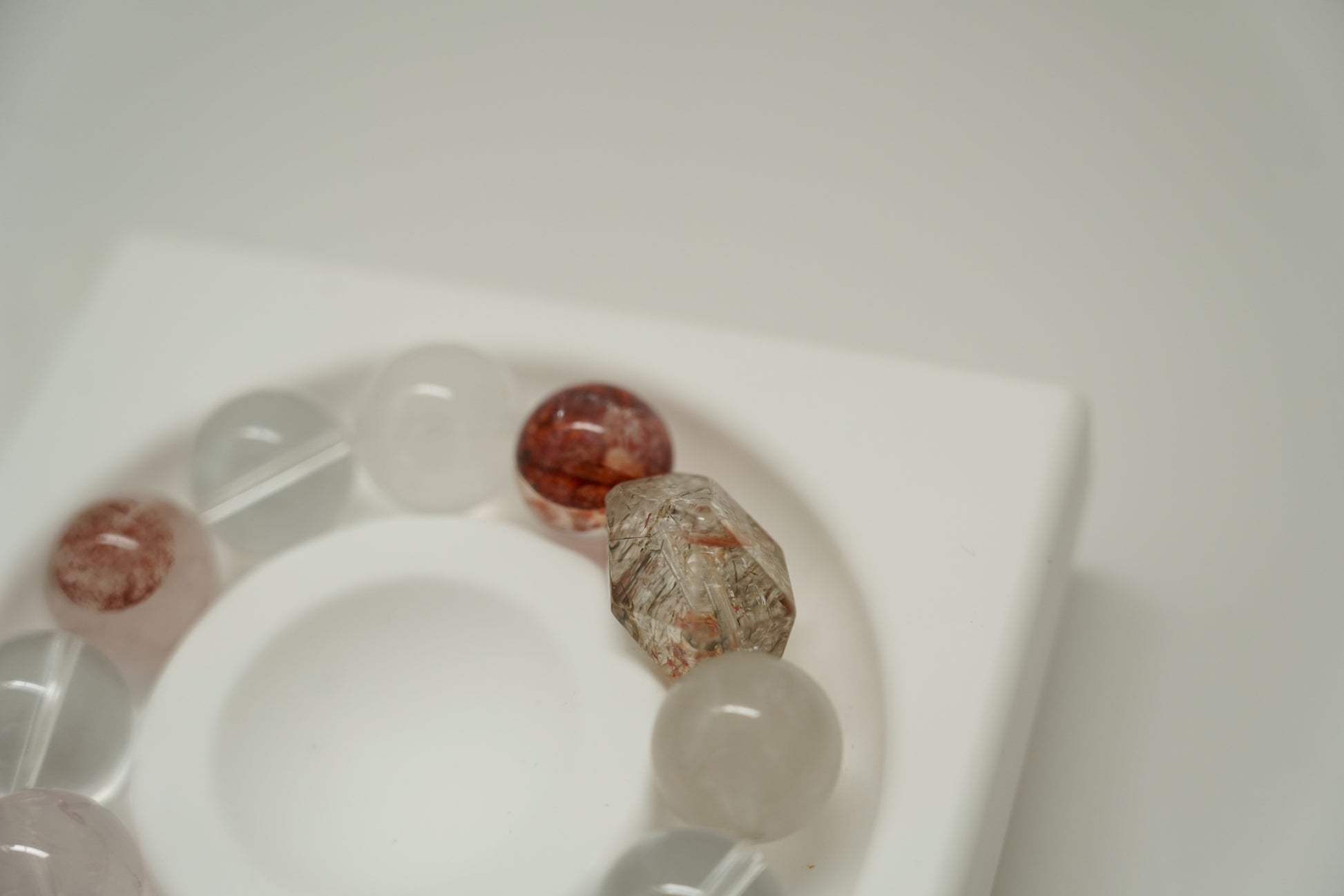 Close-up of a crystal bracelet with various beads on a white surface